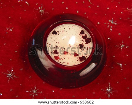 Red candle lying on red background with little hearts