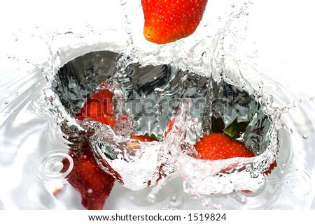 Strawberries splashing in water, lovely colour and great reflections on every single drop. Very sharp, you can see the texture of the fruit.
