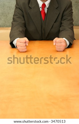 Business-man sitting at the desk, showing both fists.