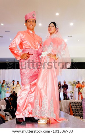 LUMUT, MALAYSIA - APR 22: A pair of models walk the runway wearing Malay bridal dress during Perak Bridal Carnival at Marina Island Hall on Apr 22, 2012 in Lumut Perak, Malaysia.