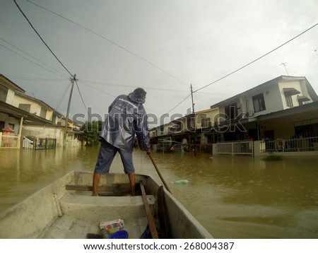 KUANTAN, PAHANG MALAYSIA-DEC 05, 2014:Unidentified boy is rowing a boat to enter his home after struck by the worst floods in history