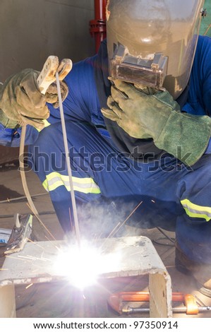 A welder with personal protective equipment welding the steel bracket