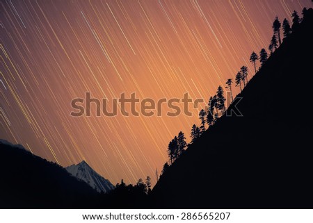 Star-fall. Stars seem to \'fall\' down behind the hill creating beautiful star-rain with snowy Himalayan peak on the second plan. Nepal, ACAP, view from the Bagarchhap village (2,160 m)