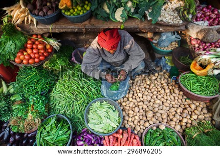 VARANASI, UTTAR PRADESH/INDIA - 8 JANUARY 2014. \
A man surrounded by vegetables and greens at his place at Indian Bazaar. A mix of colors and textures. Captured in India, Uttar Pradesh, Varanasi.