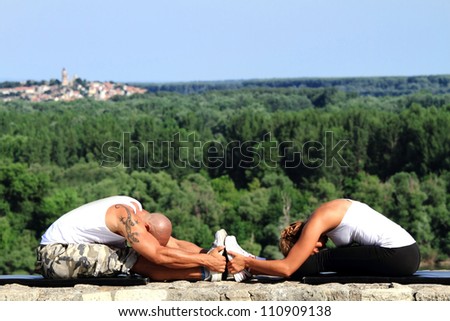 Male and female fitness instructors practising in nature. Doing stretching exercises
