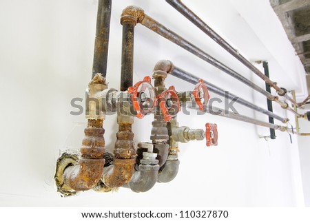 Old Heating Cooling Water Plumbing Pipes with Valves on White Wall