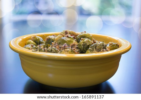 Brussel Sprouts Cooked with Pancetta Olive Oil and Onions in Yellow Bowl with Bokeh Blurred Background