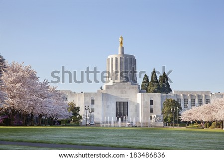 SALEM, OREGON - MARCH 23, 2014: Capitol State Building against a blue sky. Cherry Blossom Trees Blooming at Oregon State Capitol State Park in Salem Oregon during springtime. A tourist attraction.