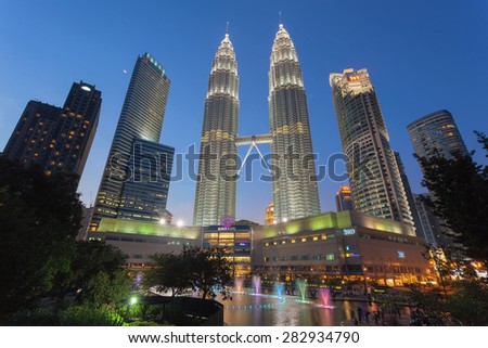 KUALA LUMPUR, MALAYSIA - FEBRUARY 3, 2014: Water Fountain at Suria KLCC with Petronas Towers and Office Buildings at Blue Hour at Night. It\'s a popular shopping attraction to locals and tourists.