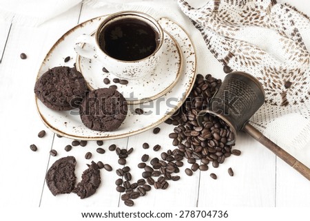 Cup of coffee,turk coffee maker and coffee beans on wooden background