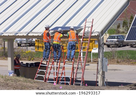 MAY 22, 2014: Workers at Great River Energy install solar carport in Maple Grove, Minnesota. The building earned an award given to facilities that demonstrate energy efficiency and sustainability.