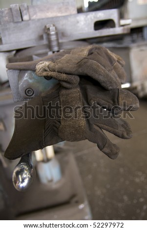 Pair of well worn working gloves resting on shop press