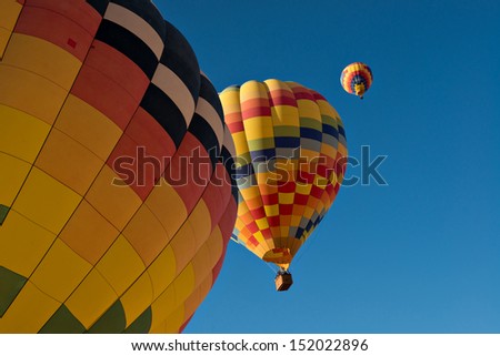 Three hot air balloons just after lift off.  Set against a deep blue sky.
