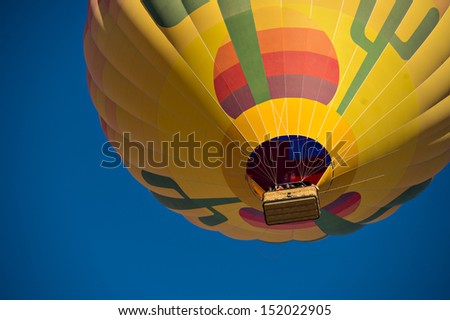 Looking up at a colorful hot air balloon just after lift off.  Set against a deep blue sky.