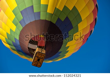 Colorful hot air balloon just after lift off.  Set against a deep blue sky.