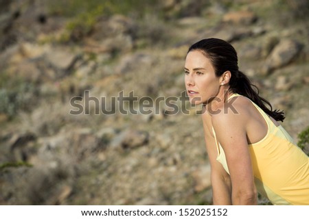 Young woman stretching to warm up for a trail run outdoors at South Mountain Park in Phoenix, Arizona.