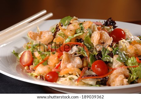A garden salad with cherry tomatoes, shrimp and crispy wonton strips