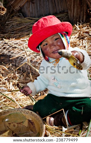 TITICACA, PERU - AUGUST 22, 2008: Unidentified Indian child welcomes tourists & shows off his fish on Uros in Titicaca. The Qhichwa Uros are pre-Incans who live on 42 self-fashioned floating islands.