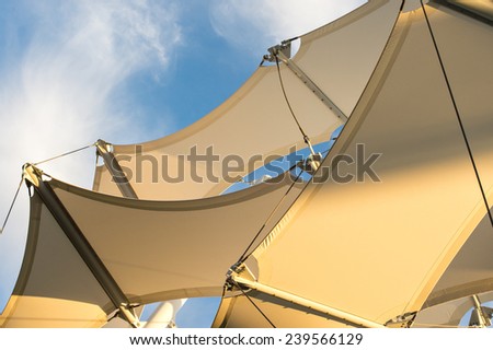 Canopies anchored to steel structures provide shade at an outdoor pavilion.