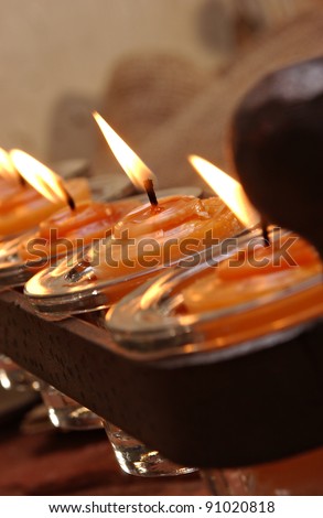 A wrought iron candle holder with orange scented lit votive candles.