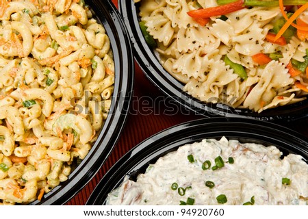 Macaroni salad, pasta salad and potato salad in containers ready to be served.