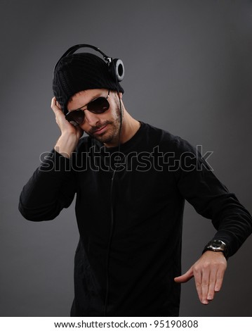 DJ listening to headphones on a dark background.  His hand is out as he is about to spin a record.