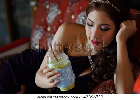 Young Asian woman holding a green tea smoothie, Model is Thai Ethnicity