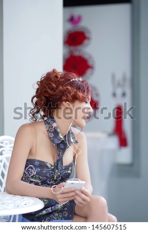 Happy woman using smartphone listen to music while sitting at outdoor cafe, model is Thai Ethnicity,