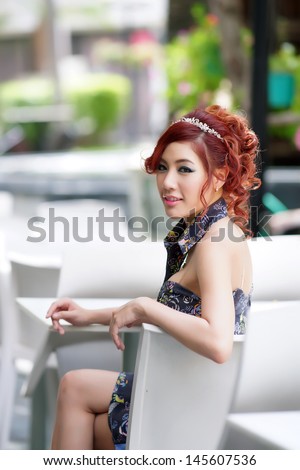 Beautiful young woman sitting alone in street cafe, Model is Thai Ethnicity.