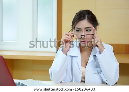 Young woman doctor with laptop and headache in doctor\'s office