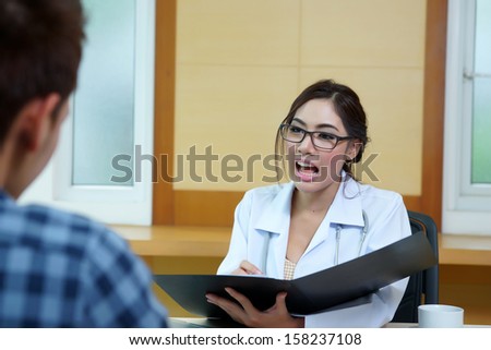 Woman doctor talking to her male patient at office, Mode is Thai ethnic.