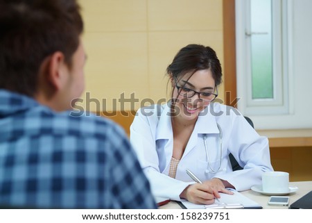 Woman doctor talking to her male patient at office, Mode is Thai ethnic.