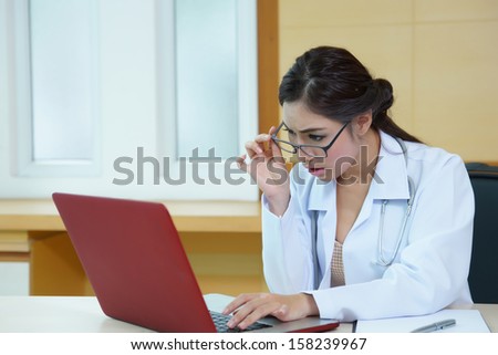 Young female doctor looking at laptop screen and surprised, Model is Asian woman.