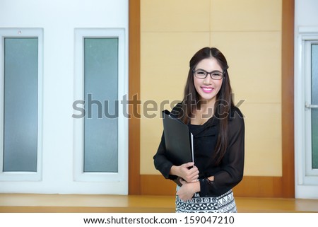 Portrait of confident young businesswoman with file folder in office