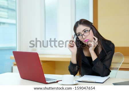 Young business woman thinking with a pen in hand at her workplace.