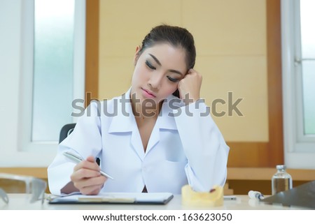 Bored woman dentist looking very boring at her desk.