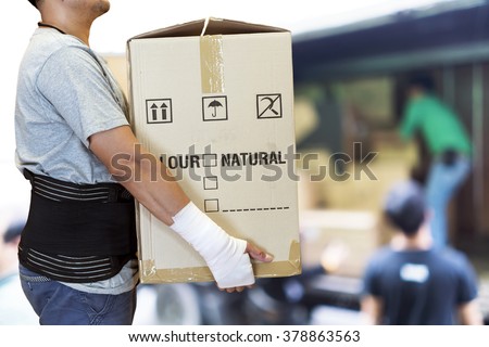 Man hand bandage, lift heavy carton wearing support belt for protect his back, blurred background of worker lift cartons