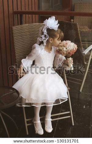 beautiful little girl as a bridesmaid sitting on the chair with the beautiful bouquet