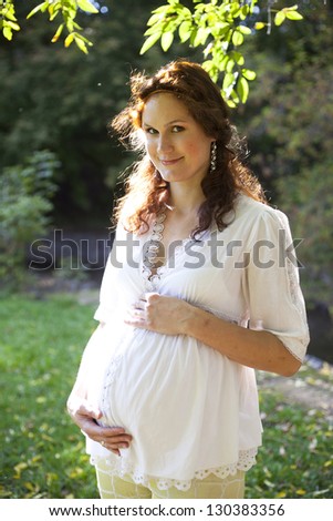 beautiful pregnant red head woman on summer background