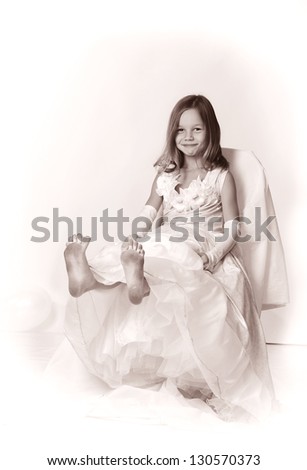 little sly girl sitting in white dress showing her dirty feet black and white portrait