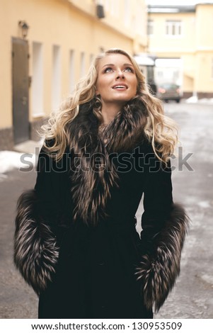 Beautiful blond girl wearing winter coat on the street back yard background
