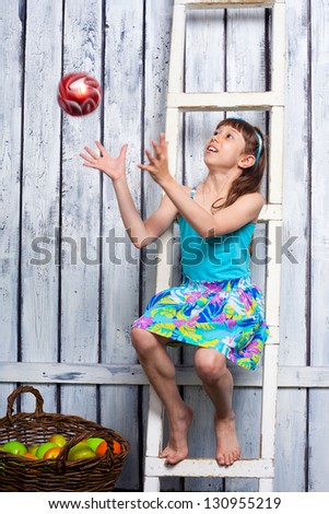 preteen pretty girl sitting on the ladder and playing with ball in the garden