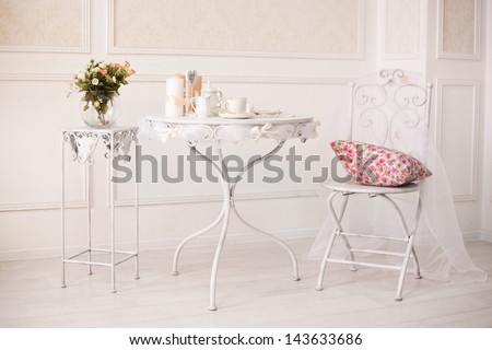 Vintage White Room With Chair And Table With Flowers Pillow, Coffee Cups And Candles