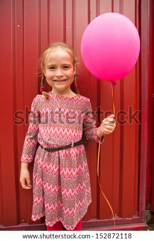 little girl with pink balloon in the summer garden