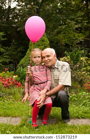 grandpa and grand daughter in the summer garden with pink balloon