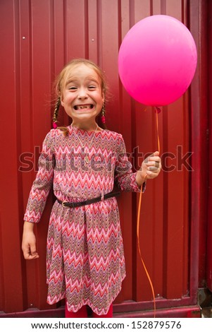 little girl with pink balloon making funny grimace
