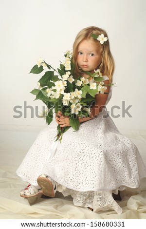 little blond girl in white dress with jasmin flower