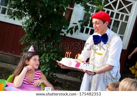 birthday party for preteen girl with clown carrying cake with burning candles