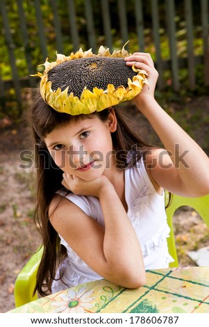 beautiful preteen girl with long dark hair holding sunflower on summer background