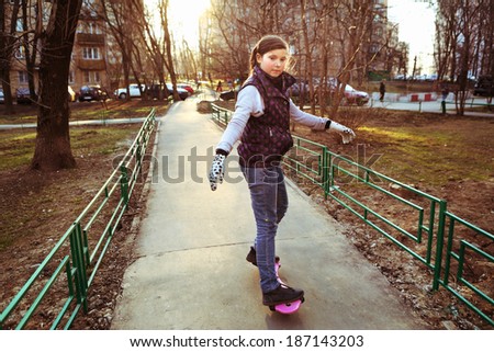 pretty teen school girl riding street board on the urban background